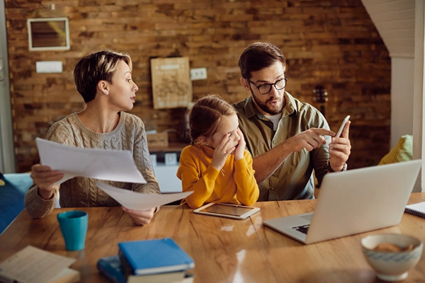 Man and woman are frustrating working on a laptop while tween girl sits between them. 