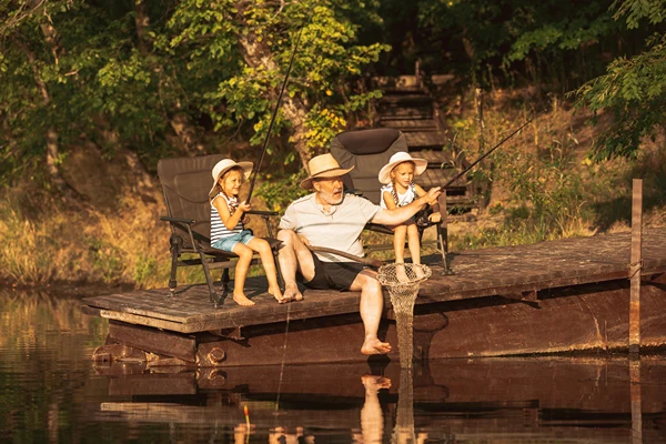 Grandpa fishing from dock with his two grand daughters.