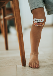 A child appears to be limping with bandages on their knee.