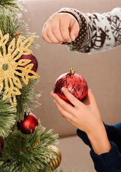 Boy and girl place a decoration on the Christmas tree together.