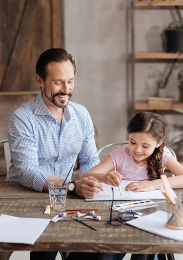 Dad and daughter working on a project at dining room table.