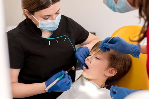 A female pediatric working on a sedated boy's teeth.