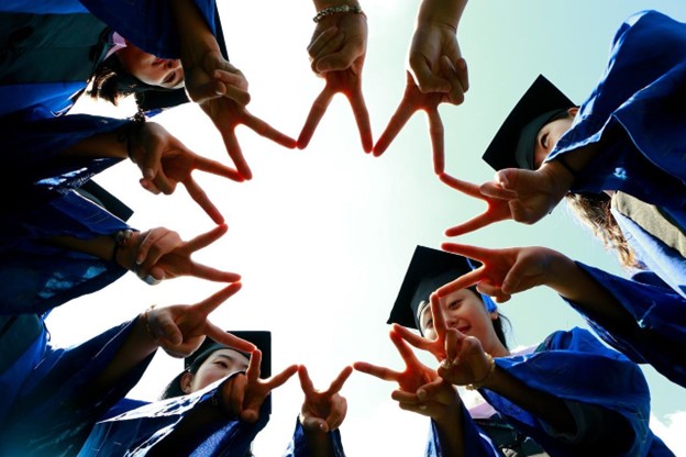 Group of grad students point their fingers together in a circle.