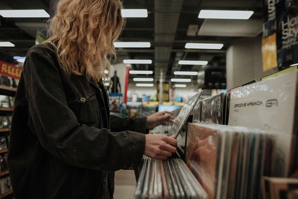 A person with long hair browsing for music in a record store.