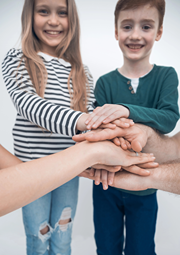 Family stacks hands in support of each other, like a team.