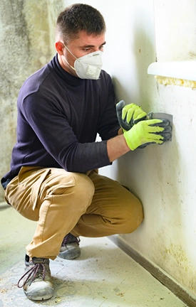 Man wearing filtration mask tests for mold in a house.