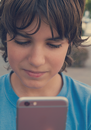 Teen boy looking intently at his smartphone.