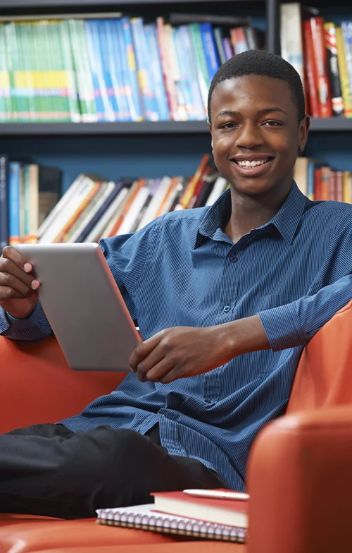 Male college student reading in library.