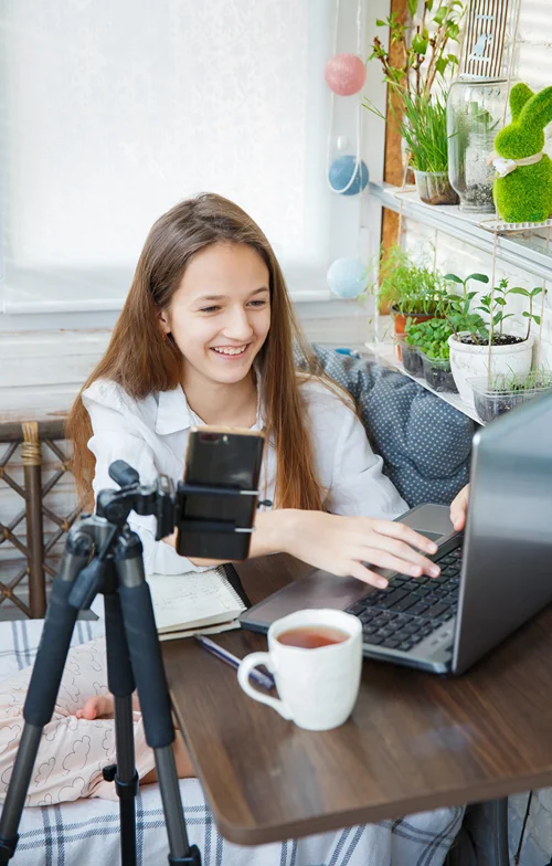 Girl vlogging with camera in front of laptop.