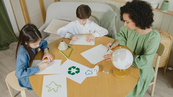 Mother, son, and daughter drawing signs about recycling.