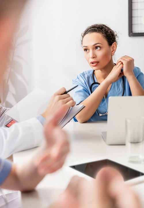 Confident nurse addressing collegues in a meeting.