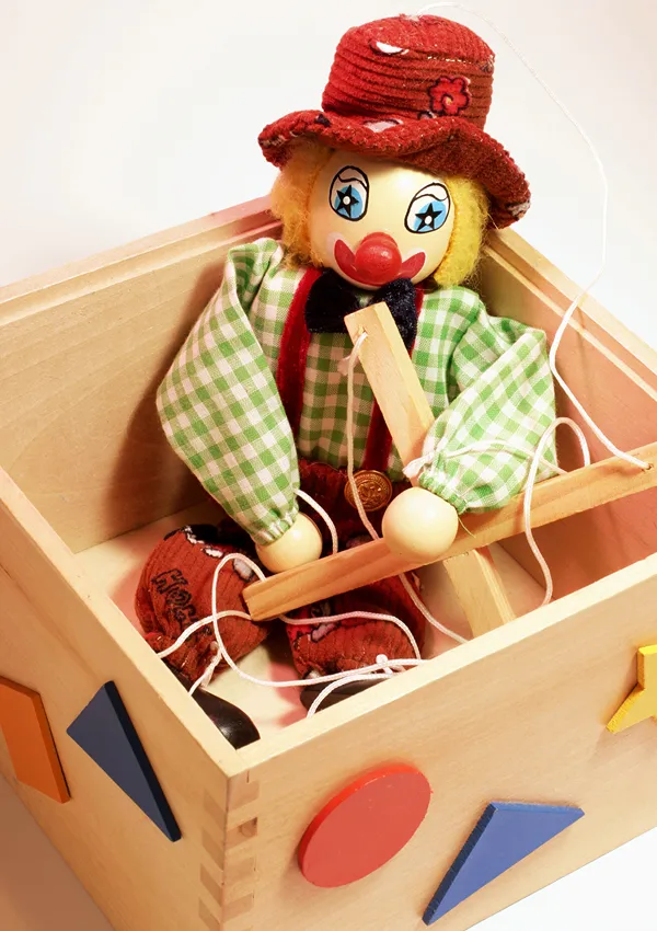 A string puppet sitting in a wooden box.