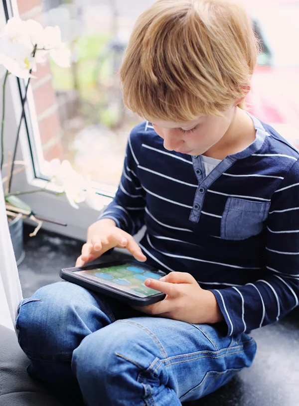 Boy engaged in an educational game on his tablet.