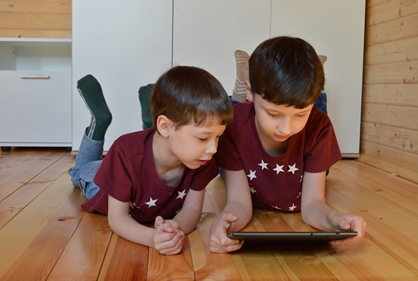 Boys on floor watching tablet.