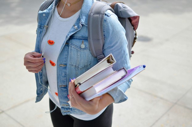 Body shot of a teen girl with backpack and school books in her arm.