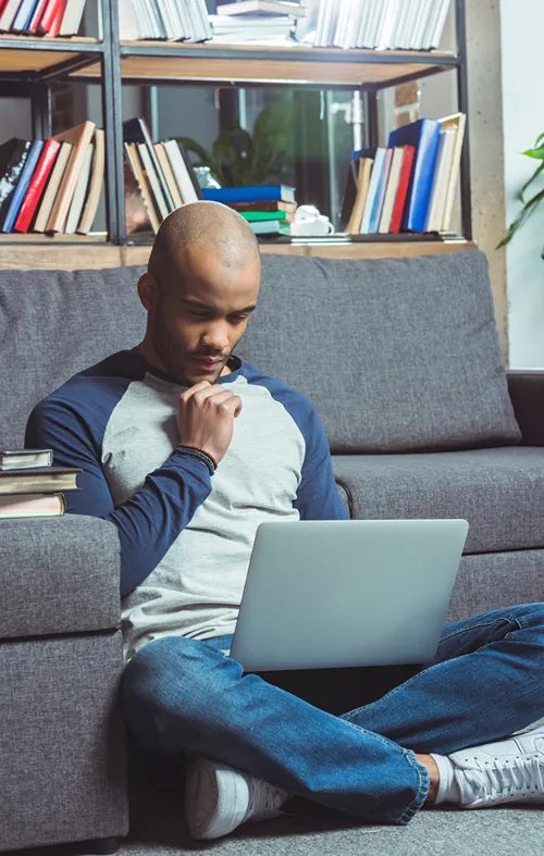 Male black student at home intently studying on his laptop.