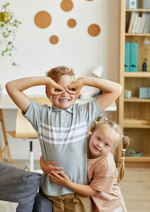 Girl hugs brother as he makes a funny face.