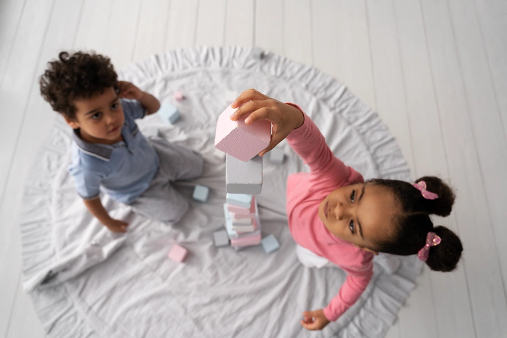 Two young children playing with blocks on an area rug.