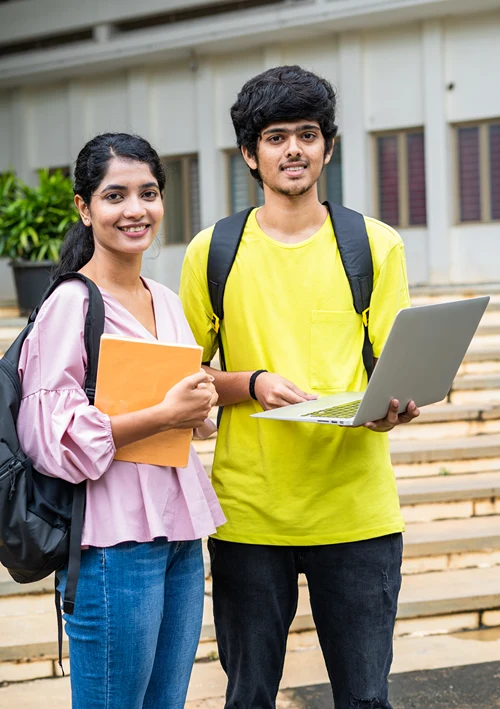 Female college student holding book with male student holding his laptop.