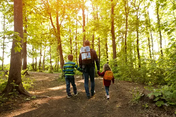 Dad with son and daughter exploring the wilderness on a forest pathway.