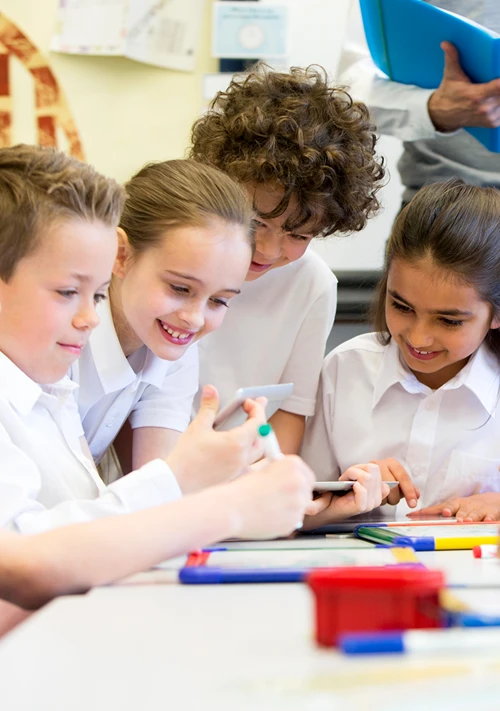 Kids in school uniforms gathered at a table in their classroom.