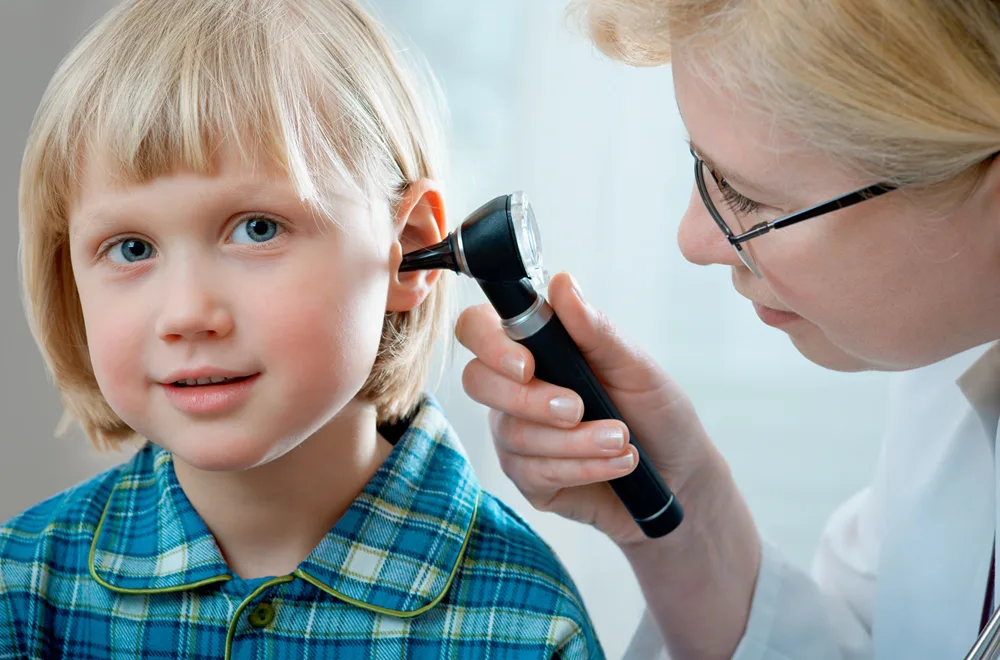 Doctor checking in girl's ears during examination. 