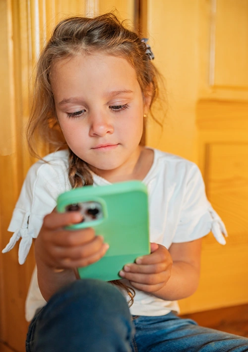 A little girl deeply engaged on her smartphone.