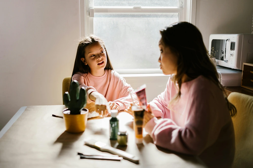 Mother and daughter talking at the kitchen table.