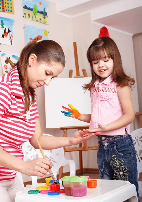 Mom is teaching her child how to paint on an easel.