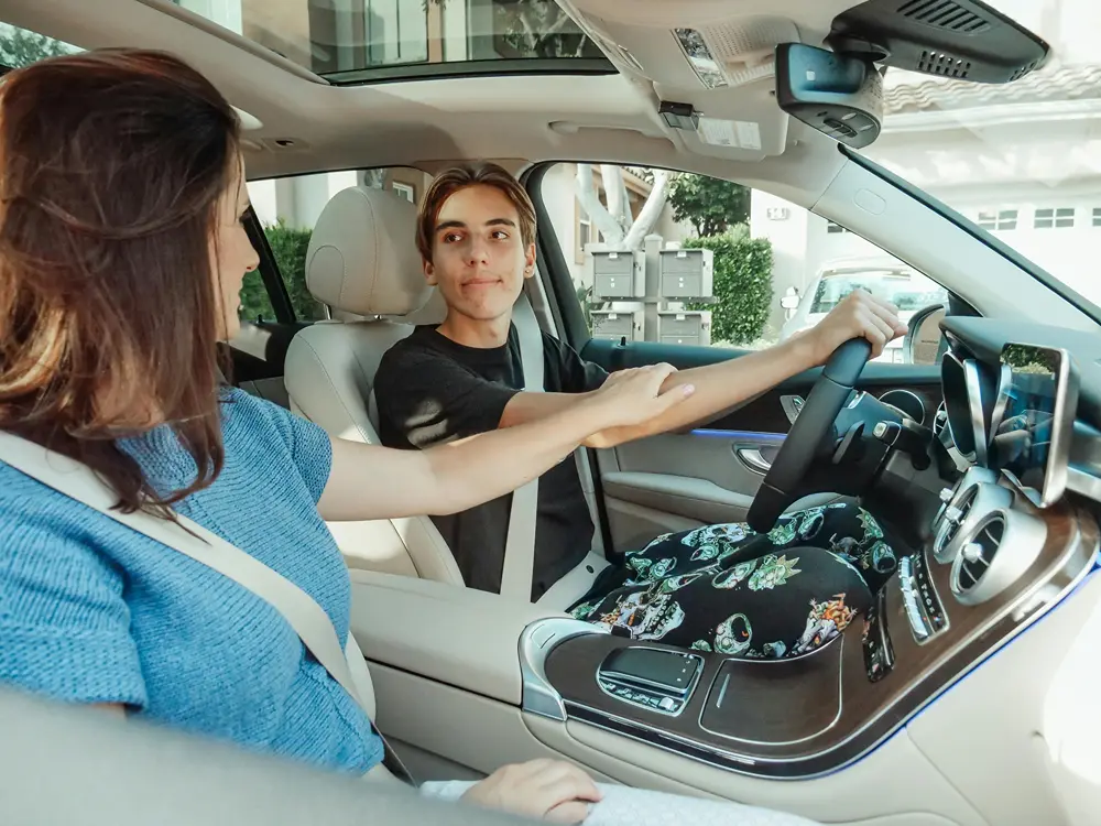 Mother in passenger seat encouraging her son is about to drive onto a street.