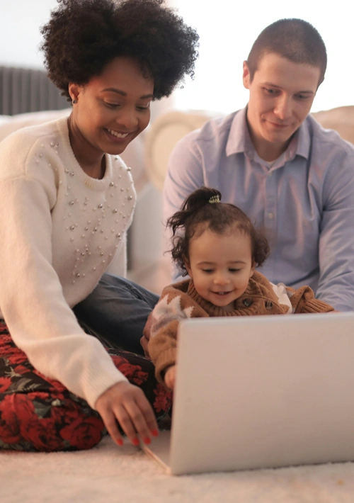 Parents and toddler sitting on the floor using a laoptop