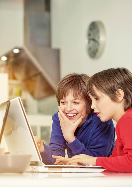 Two boys having fun surfing the internet on a laptop.