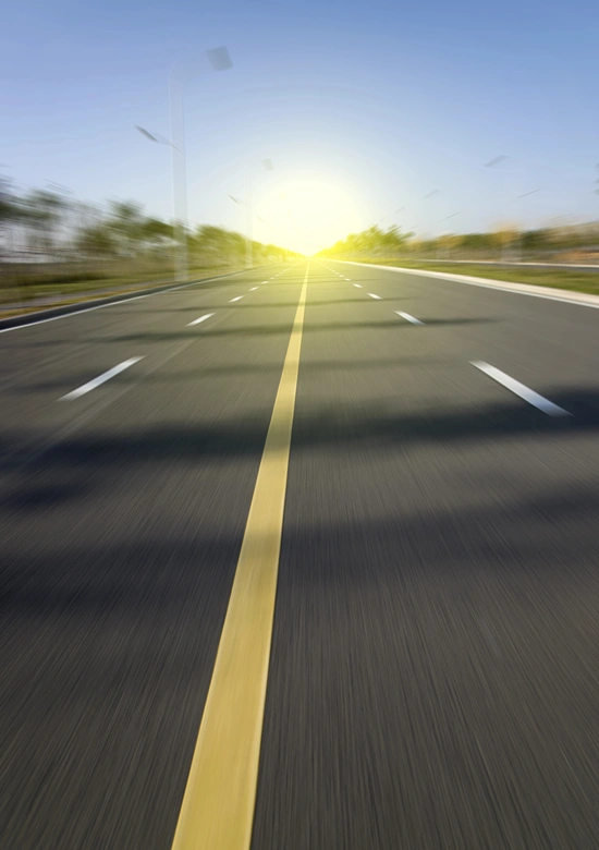 Bright sun in the distance of a long empty highway.