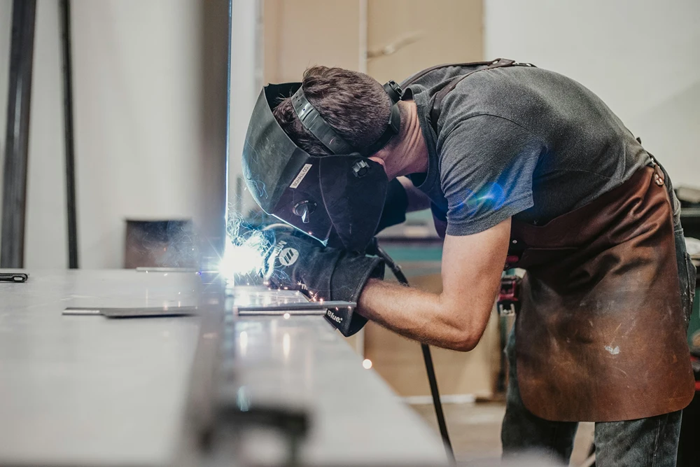 A male student is welding in shop class.