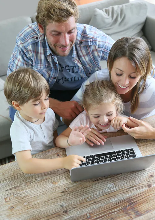 Parents and two children playing a puzzle game on a lap top.