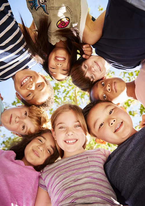 A mixed group of children looking down at camera.