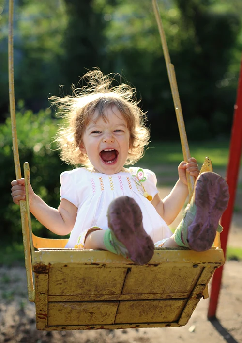 Extremely happy toddler having fun on a swing