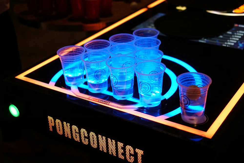 A table scattered with plastic cups filled with alcohol.