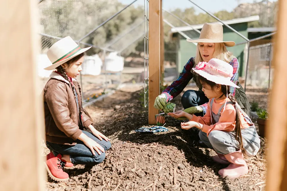 Teacher with two girls in a small garden during field trip.