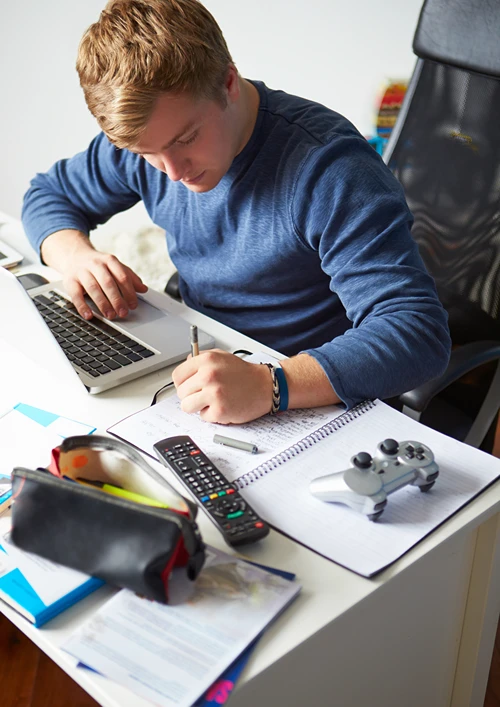 Teen boy studying at his bedroom desk.