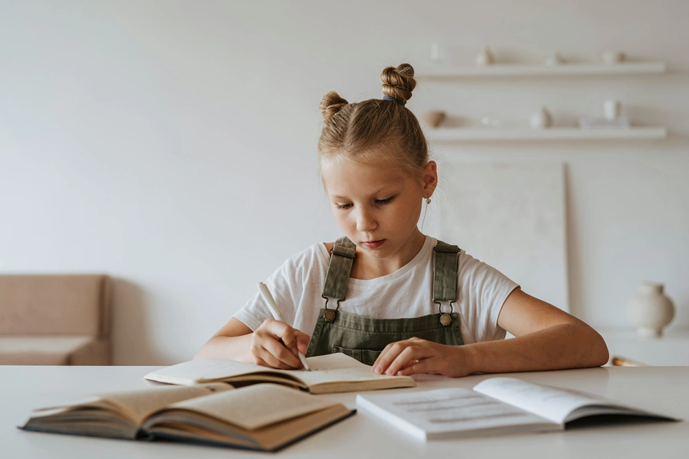 Tween girl doing studying at home on table.