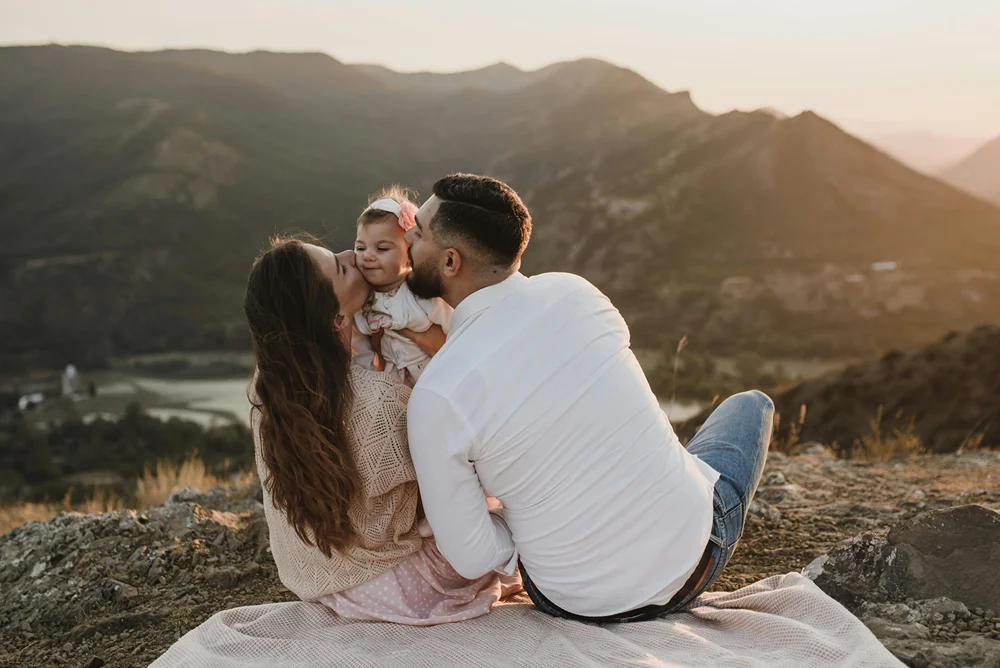 Parents with baby seated on a blanked overlooking a valley view