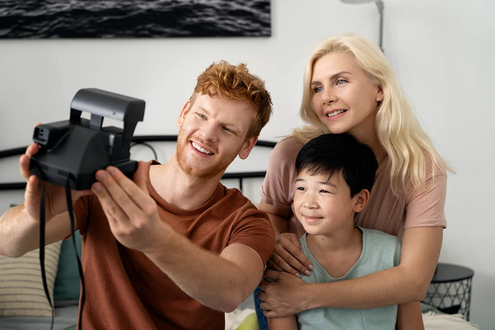 Dad, mom, and son taking a selfie of themselves with an instant film camera