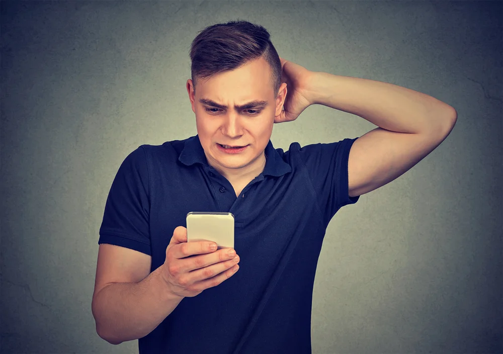 Utterly frustrated man anxiously looking at his smartphone.