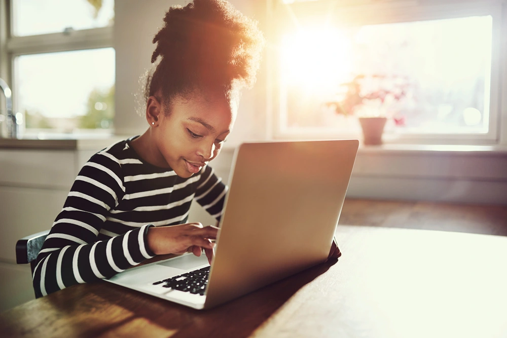 Girl along typing a message on her laptop.