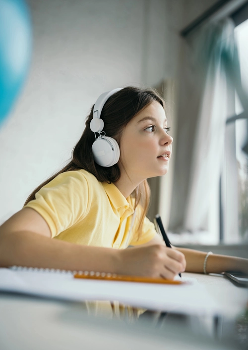 A tween girl engaged with online leaning with head phones.