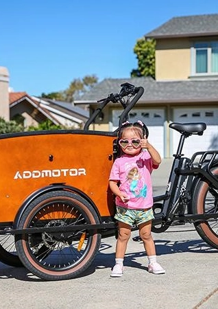 Little girl standing in front of electric cargo bike.